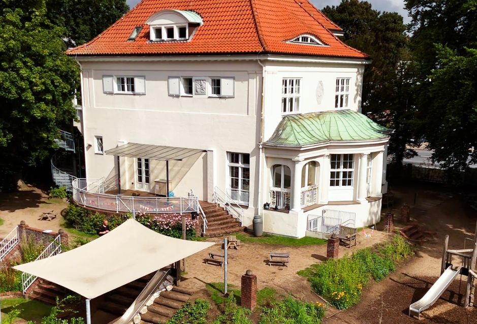 Historisches Gebäude des Stadtküken Kindergartens mit Garten und Spielplatz.